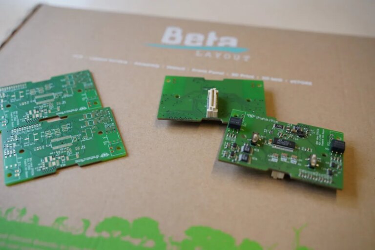 Mehrere grüne Platinen der Firma Beta LAYOUT GmbH auf einem Karton.